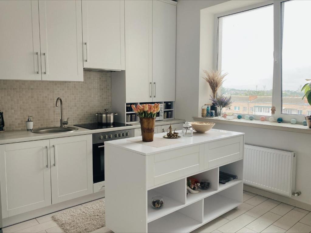 a kitchen with white cabinets and a counter with flowers on it at Стильна квартира студія у центрі міста in Lutsk