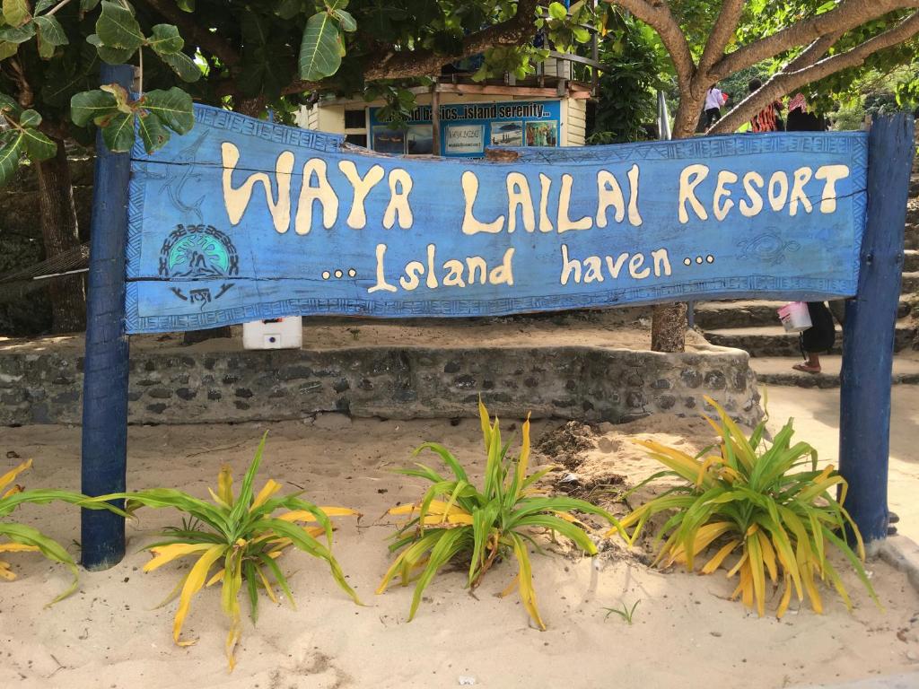 a blue sign on the beach with some plants at Waya Lailai Eco Haven in Wayasewa Island