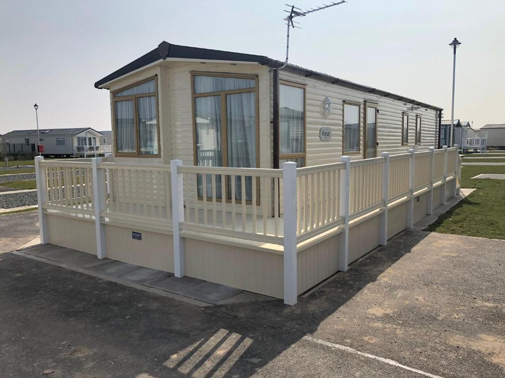 a small house with a white fence around it at Captivating 3-Bed Caravan at Golden Palm Skegness in Skegness