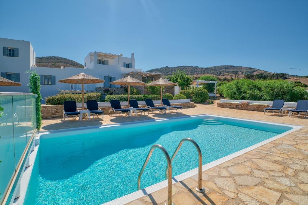 a swimming pool with chairs and umbrellas next to a building at Villa Afroditi in Antiparos