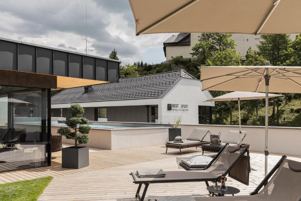 um pátio exterior com uma piscina e guarda-sóis em Rest Apartments & Suiten em Mauterndorf