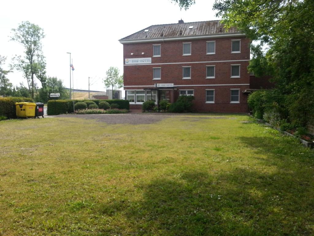 a large brick building with a large grass yard at Ems-Hotel in Emden