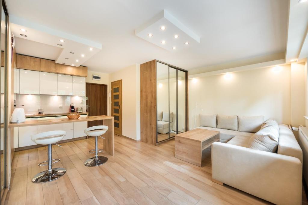 a living room with a couch and a kitchen at Mokotów Orzycka Beige Studio in Warsaw