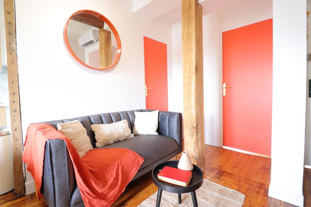 ein Wohnzimmer mit einem Sofa und einem Spiegel in der Unterkunft Le Boho - Charmant T3 - gare à 5 min à pieds in Bergerac