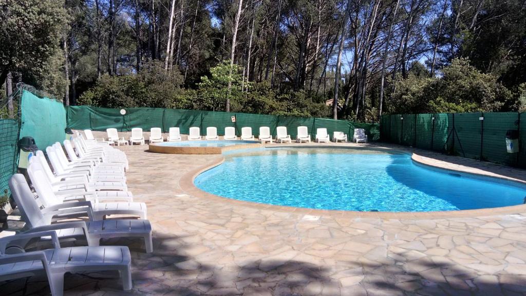 une piscine avec des chaises blanches et une clôture dans l'établissement Au petit bonheur 2, à Sanary-sur-Mer