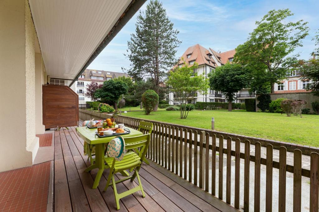 a green table and chairs on a wooden deck at Goélia Résidence Le Castel Normand in Deauville