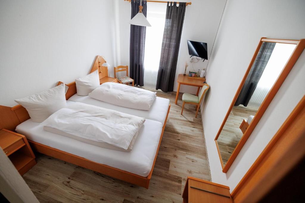 a bedroom with a bed with white sheets and a mirror at Drexl Gasthof Shiro in Schondorf am Ammersee