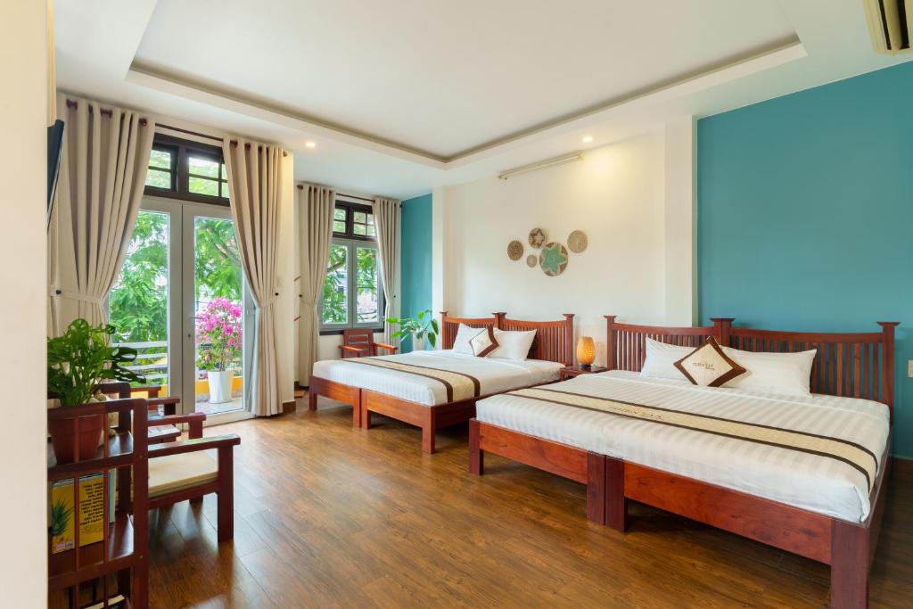 two beds in a room with blue walls and wooden floors at Thien Tan Villa with Private Pool in Hoi An
