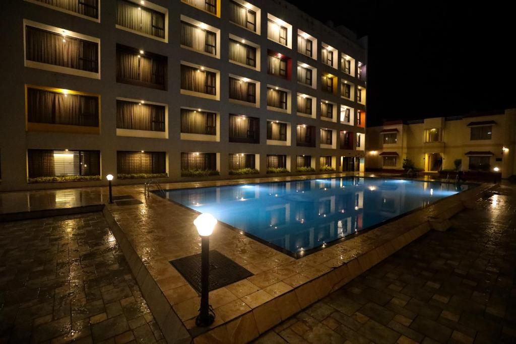 a swimming pool in front of a building at night at Hotel Atithi, Aurangabad in Aurangabad