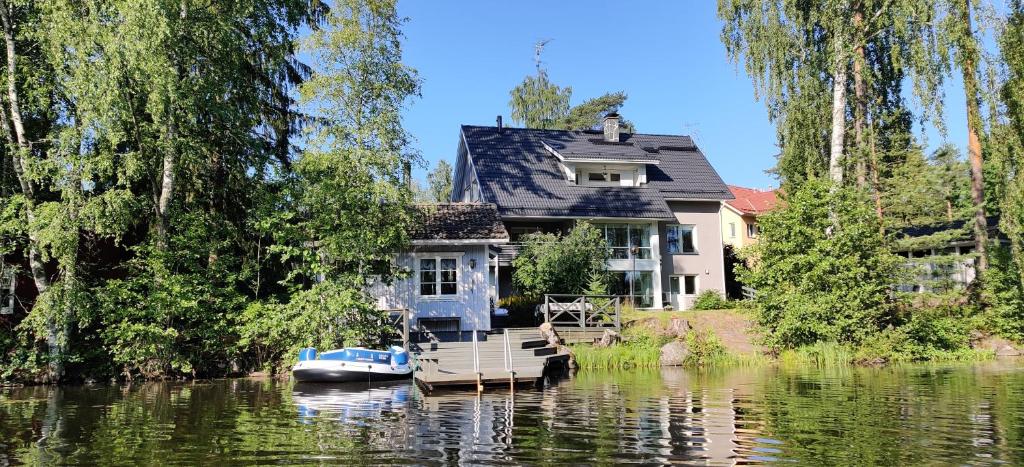 a house on a river with a boat on the water at Room by Lake 10 minutes from Tampere centrum in Lempäälä