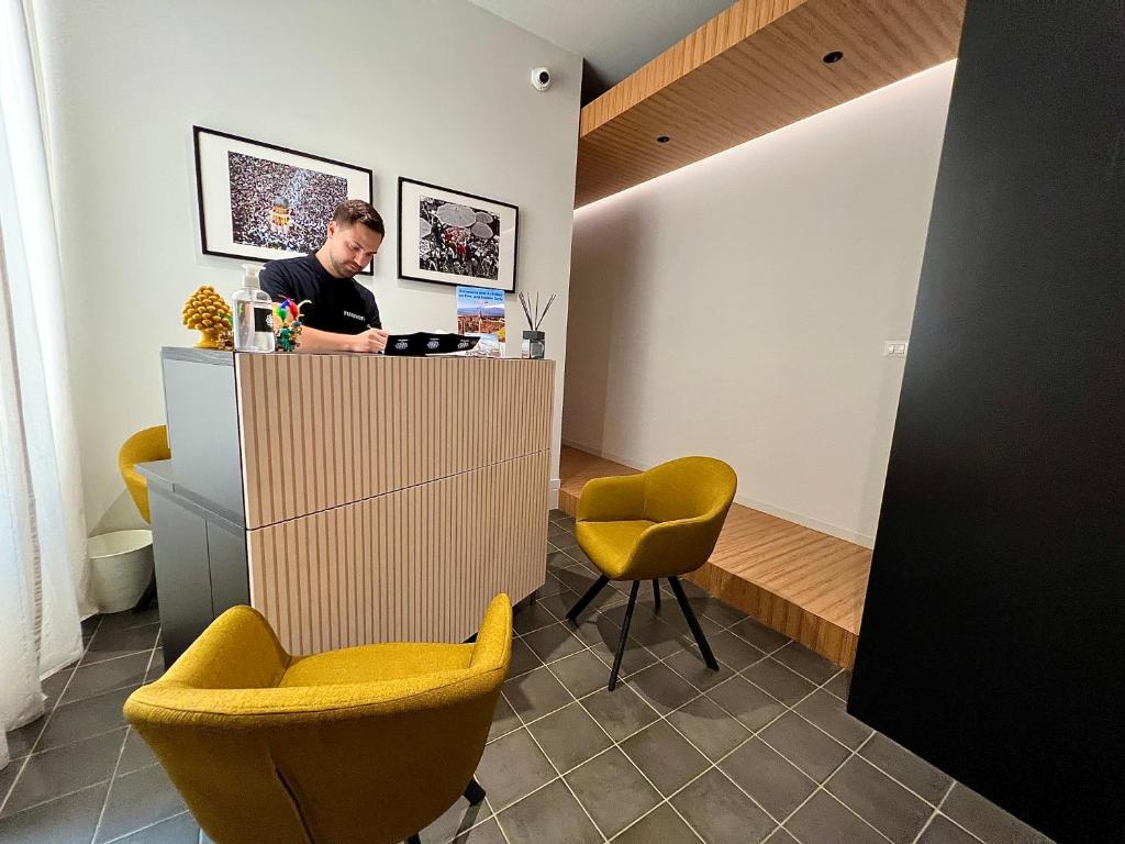 a man at a counter in a room with yellow chairs at Ruanera in Catania