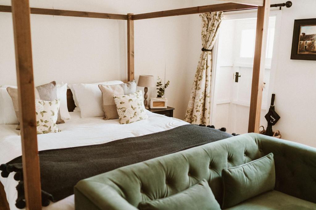 um quarto com uma cama grande e um sofá verde em Swallow Cottage, Bakewell em Bakewell