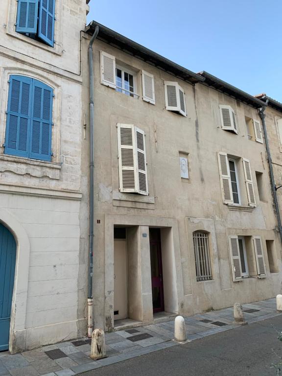 ein altes Steingebäude mit blauen Fenstern und einer Tür in der Unterkunft Appartement intra muros avec cour privée in Avignon