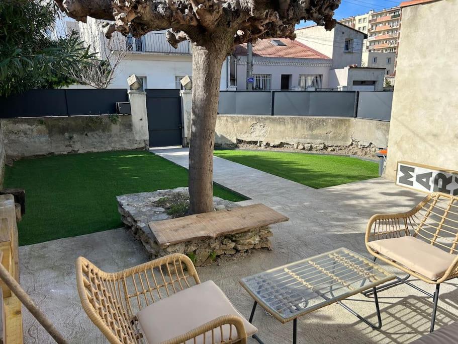 patio z 2 krzesłami, stołem i drzewem w obiekcie Villa proche centre Montpellier w Montpellier