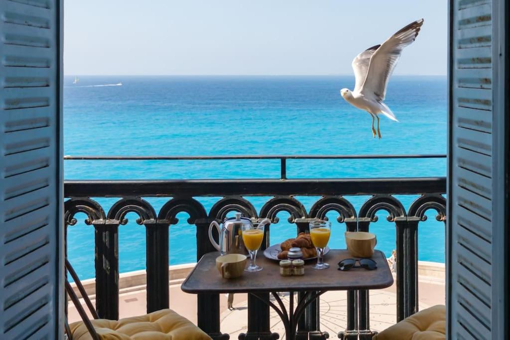 un oiseau volant au-dessus d'une table sur un balcon avec l'océan dans l'établissement L50 2P Rauba Capeu SEA View IloveNice Balcony&AC, à Nice