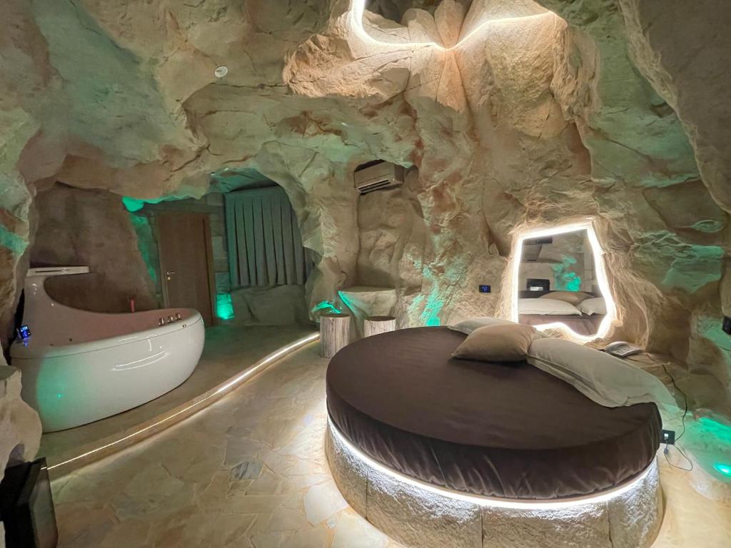 a cave style bedroom with a bathtub in a rock wall at Hotel Carosello in Pontecagnano