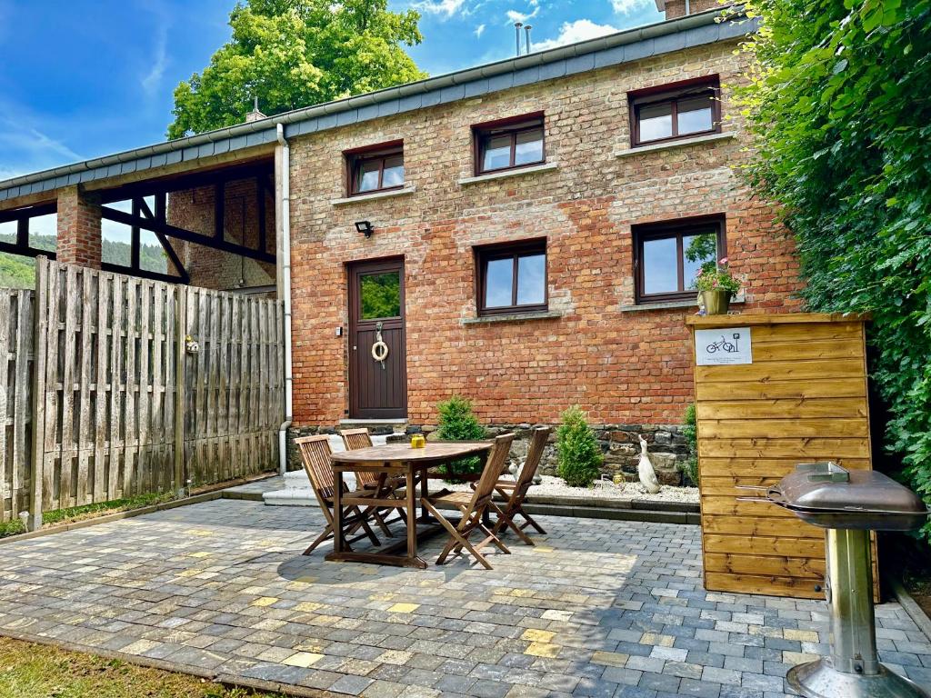 a patio with a table and chairs in front of a brick building at Sofiya Apartment in Stavelot