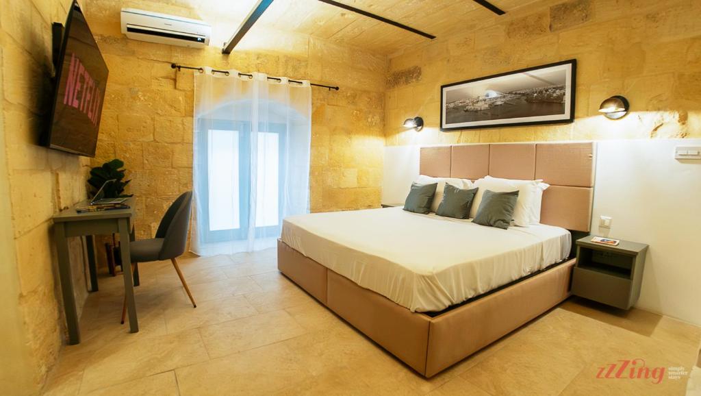 a bedroom with a bed and a desk in it at A unique 400-year-old, modern Maltese home in Birgu