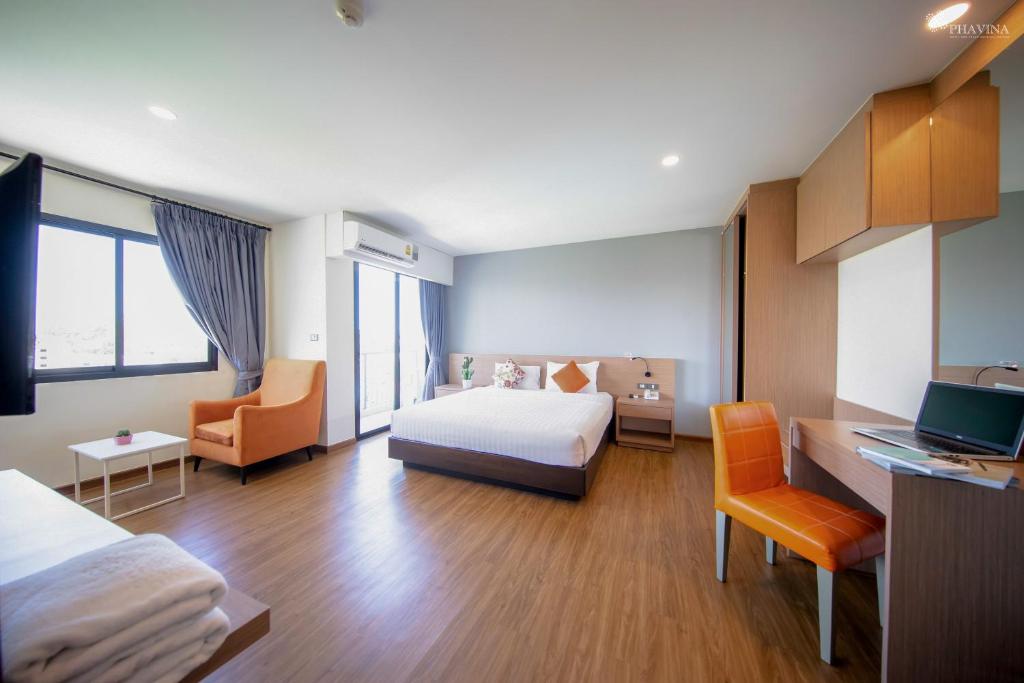 a hotel room with a bed and a desk with a computer at Phavina Grand Boutique in Rayong