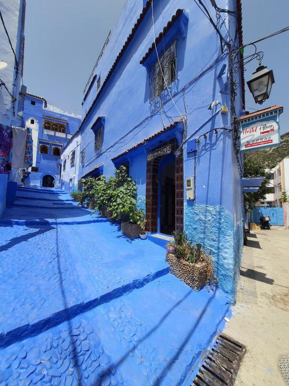 Une allée bleue avec un bâtiment bleu dans l'établissement Hostel Aline, à Chefchaouen