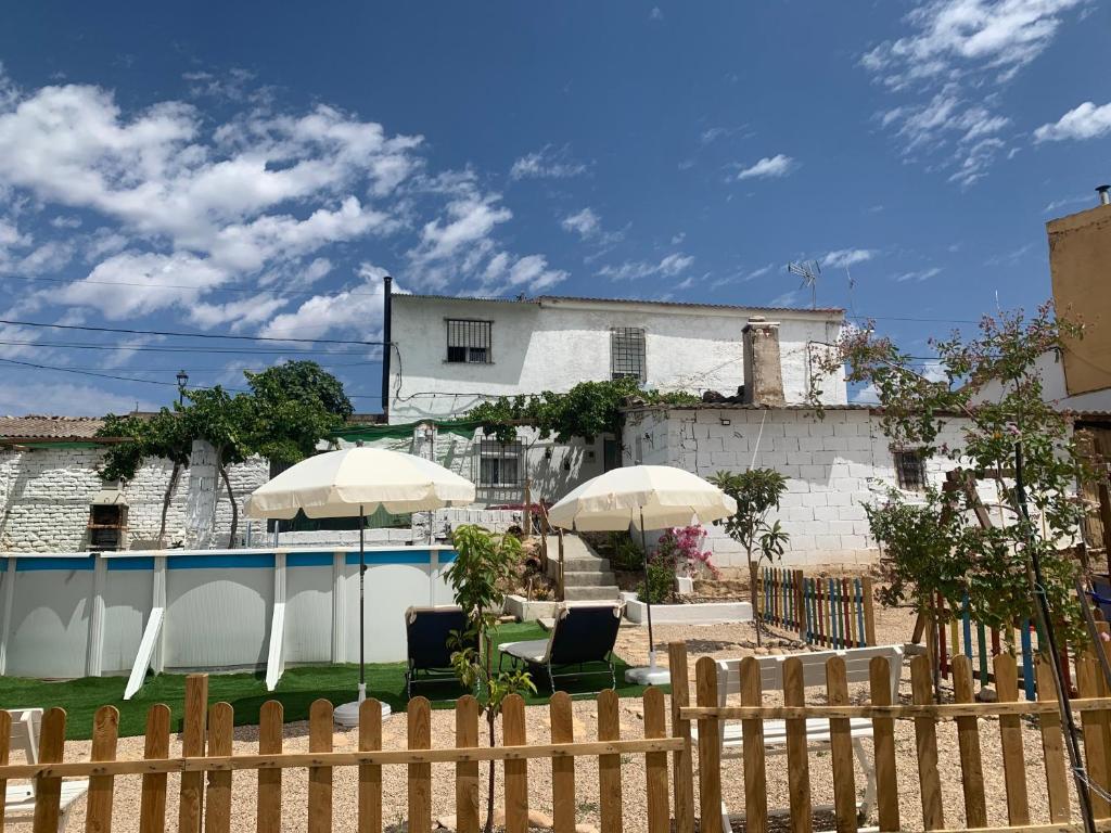 une clôture avec deux chaises et des parasols devant une maison dans l'établissement Vivienda rural Vega del Guadalquivir, à Villacarrillo