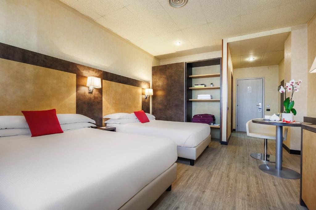 una camera d'albergo con due letti e un tavolo di JR Hotels Bologna Amadeus a Bologna