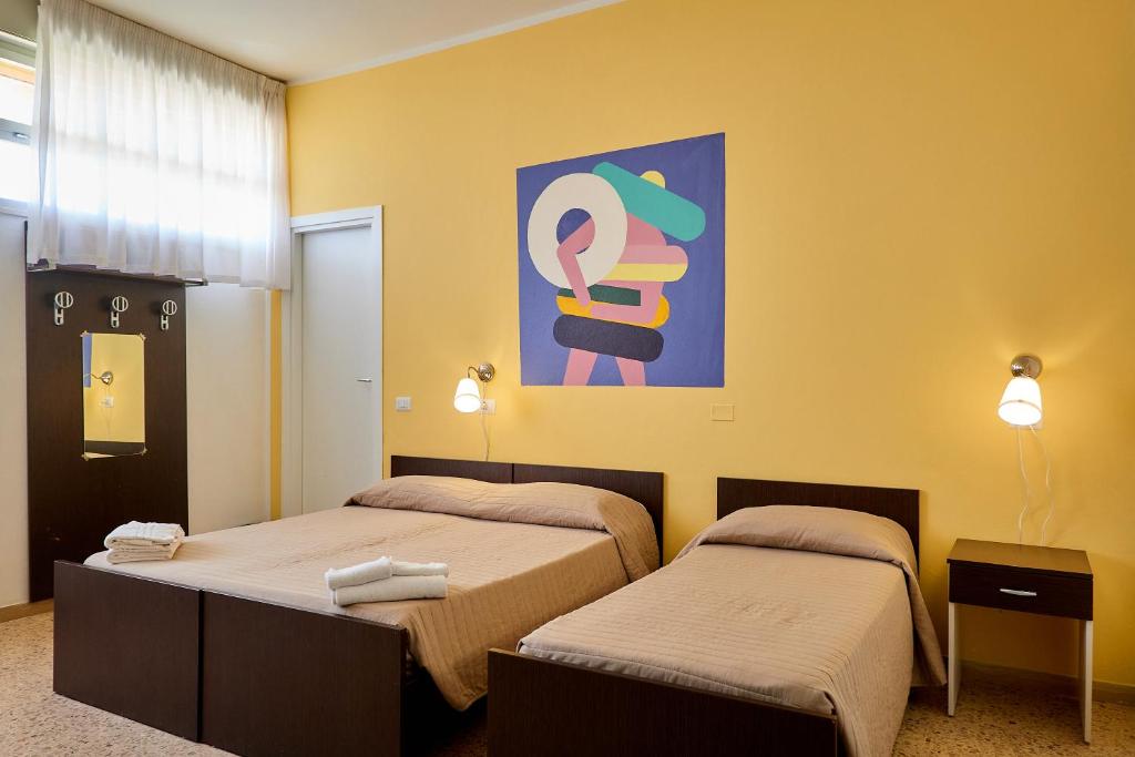 a bedroom with two beds and a painting on the wall at Soleē, Family Holidays & Hostelling in Cesenatico