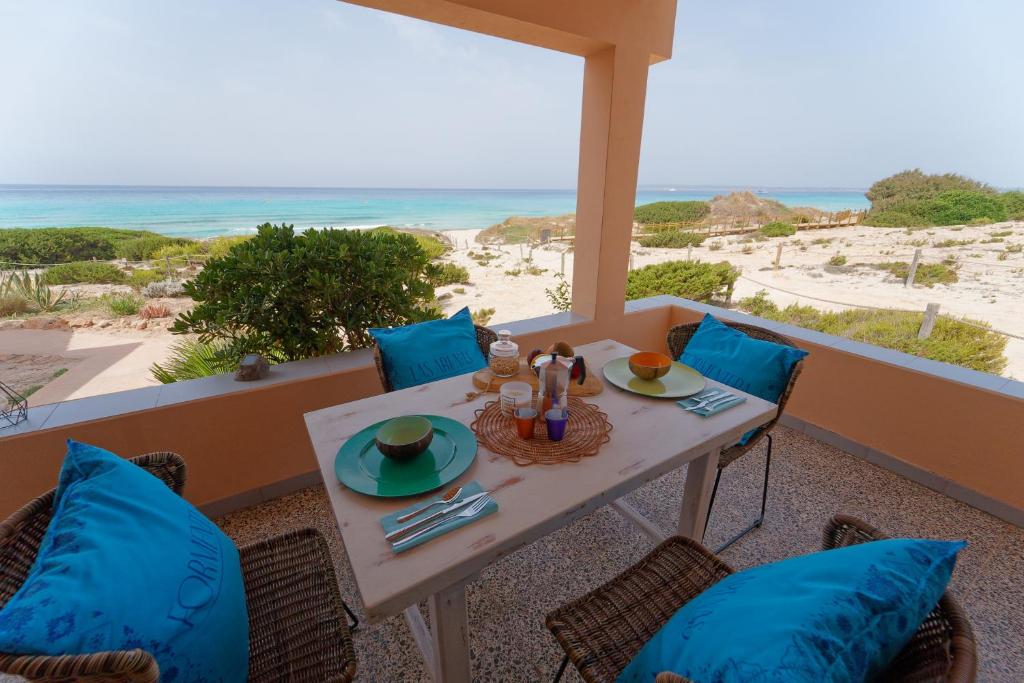 einen Tisch und Stühle auf einem Balkon mit Strandblick in der Unterkunft Arenas del Mar Formentera in Es Arenals