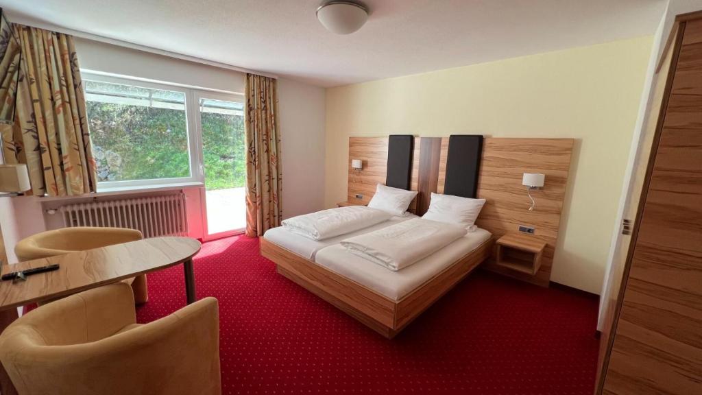 メンツェンシュヴァントにあるHotel Silberfelsenのベッド、テーブル、椅子が備わるホテルルームです。