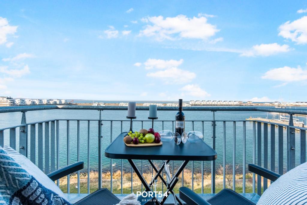 a table with a plate of fruit and wine on a balcony at Fjordsegler in Olpenitz