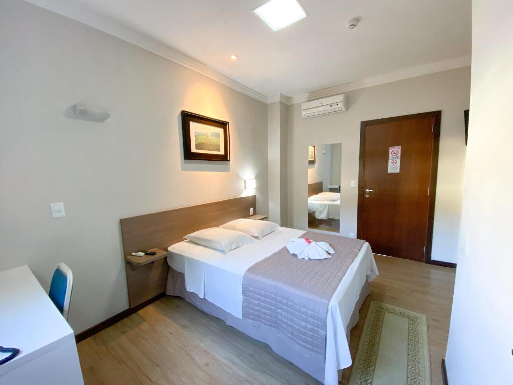 a bedroom with a white bed and a bathroom at Hotel Raul's in Gaspar