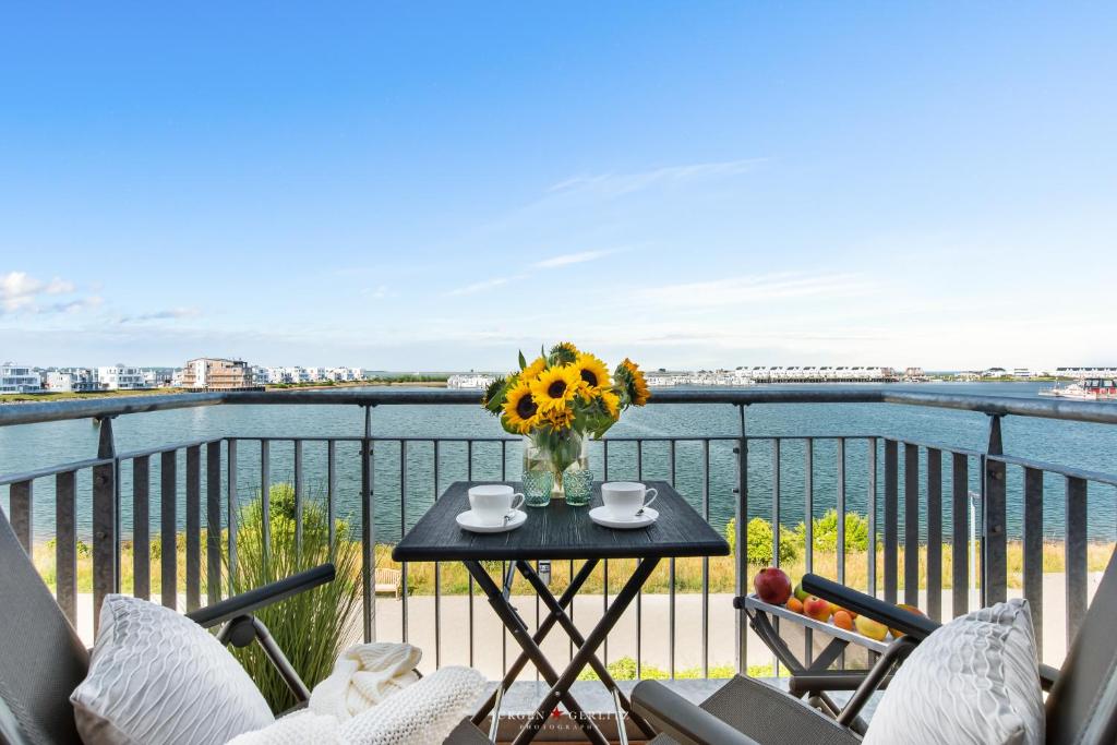 a table with a vase of flowers on a balcony at Marina Sunrise in Olpenitz