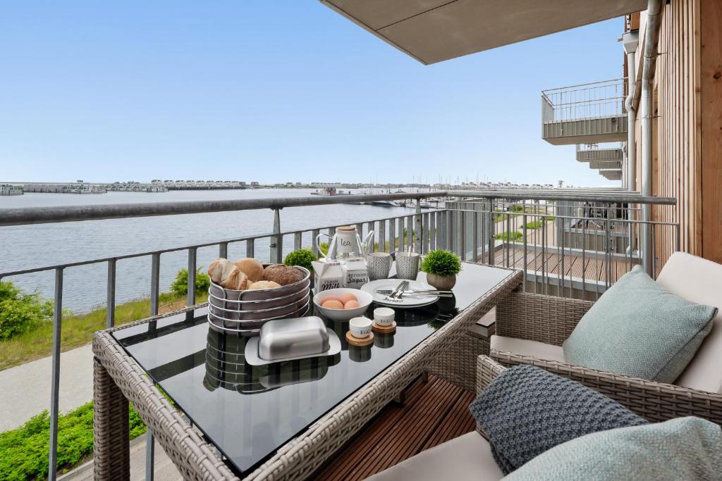 einen Balkon mit einem Tisch und Stühlen sowie Blick auf das Wasser in der Unterkunft Hafen & Meer in Olpenitz