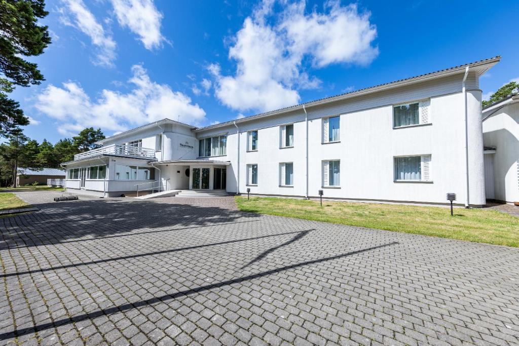 een groot wit gebouw met een stenen oprit bij Saaremaa Rannahotell ' Beach Hotel in Mändjala