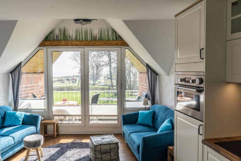 a living room with blue couches and a large window at Urlaub mit Ostseeblick, Schwimmbad, Sauna & direkte Strandlage in Kronsgaard