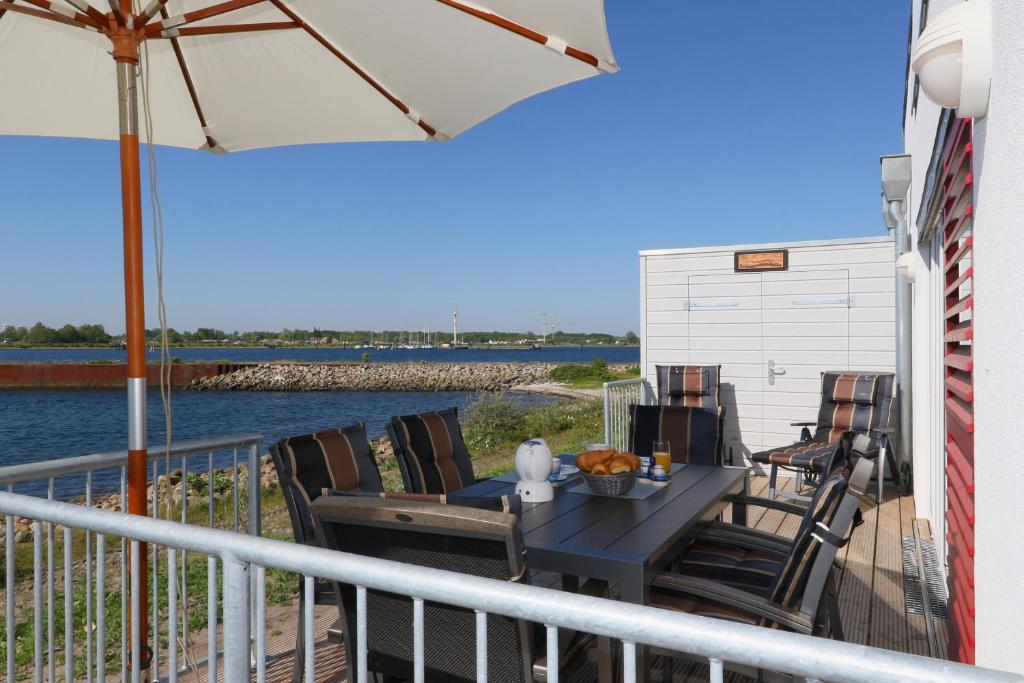 a deck with a table and chairs and an umbrella at Primavera in Olpenitz