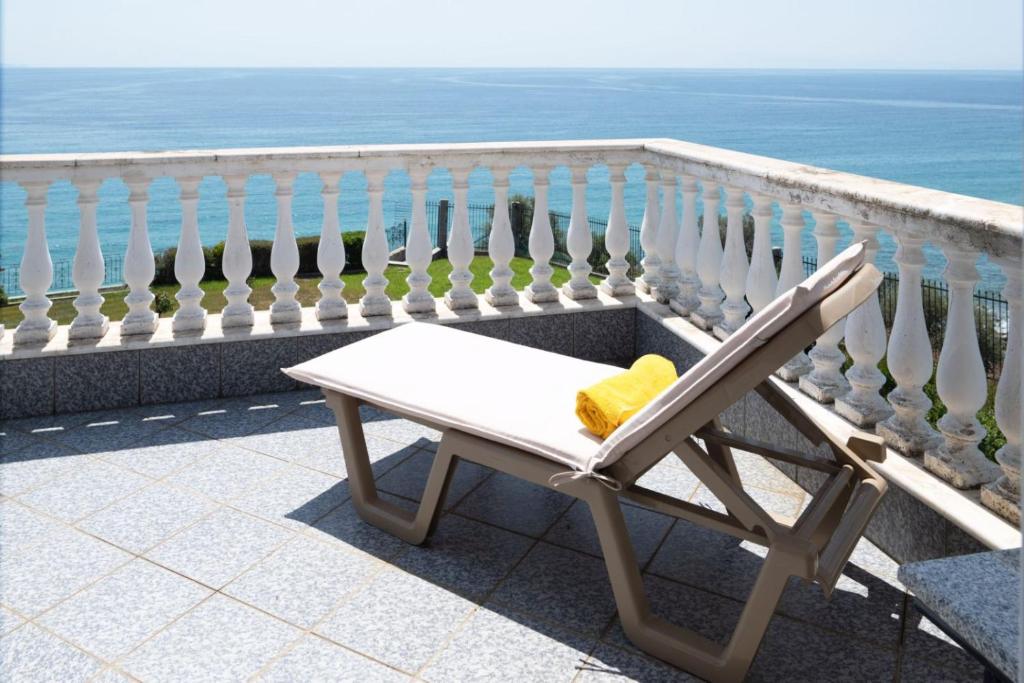a white chair sitting on a balcony overlooking the ocean at Villa Mae in Elaiokhórion
