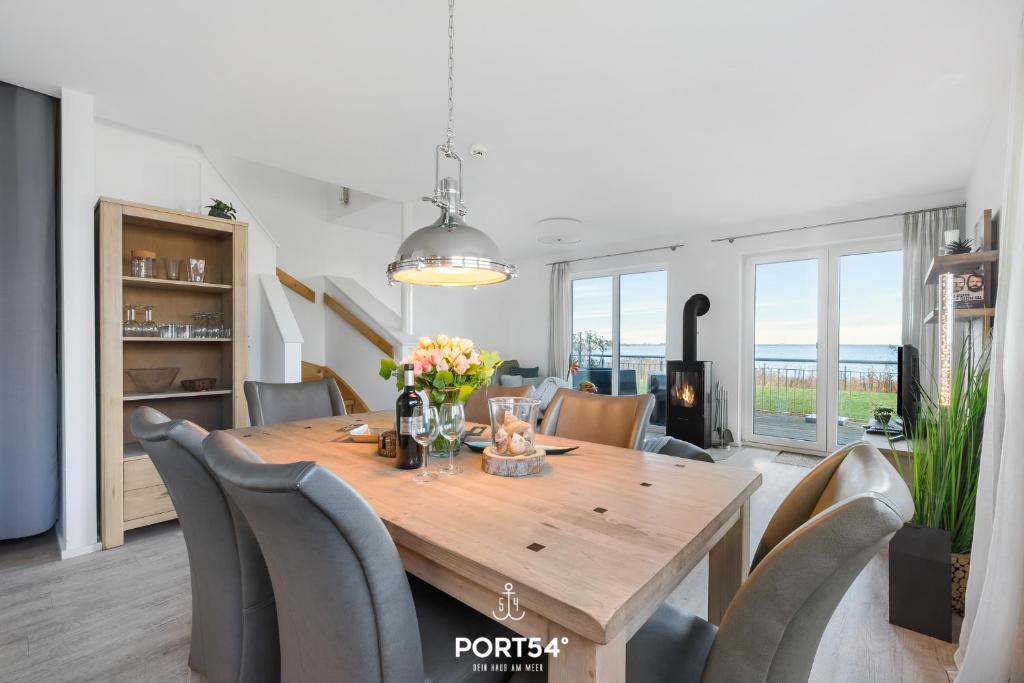 a dining room with a wooden table and chairs at Maison de la mer in Olpenitz