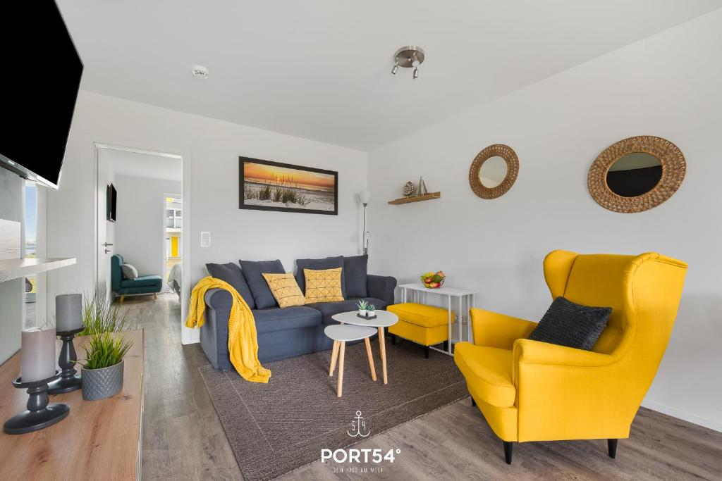 ein Wohnzimmer mit einem blauen Sofa und gelben Stühlen in der Unterkunft Ahoi Lodge in Olpenitz