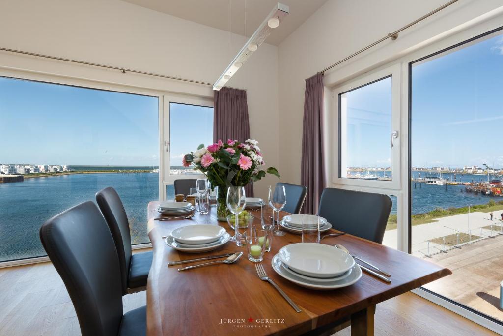 una sala da pranzo con tavolo, sedie e ampie finestre di Hafenwelt a Olpenitz