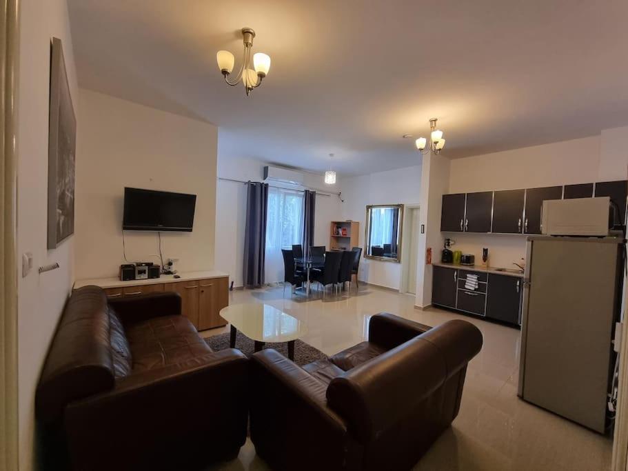 Il comprend un salon avec un canapé brun et une cuisine. dans l'établissement Modern & Spacious 3 bedroom First Floor Apartment/Villa, à Tirana