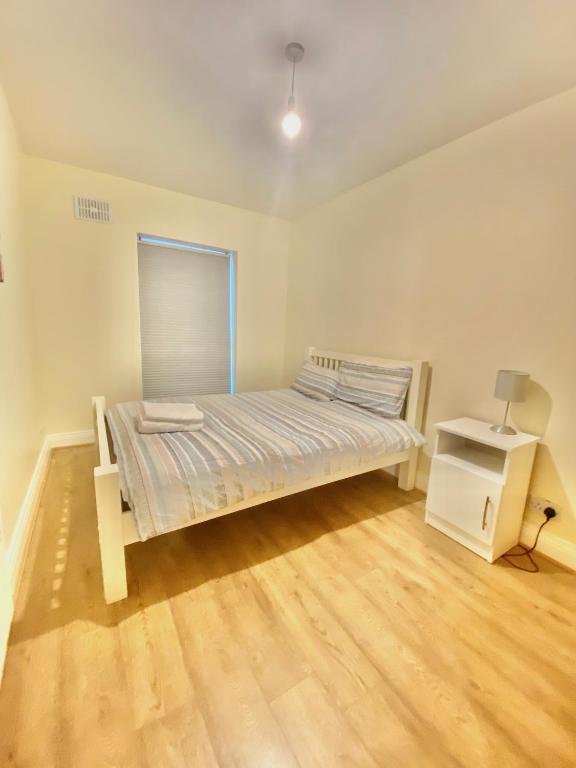 a white bedroom with a bed and a night stand at Lovely 2 bedroom apartment in Dublin City in Dublin