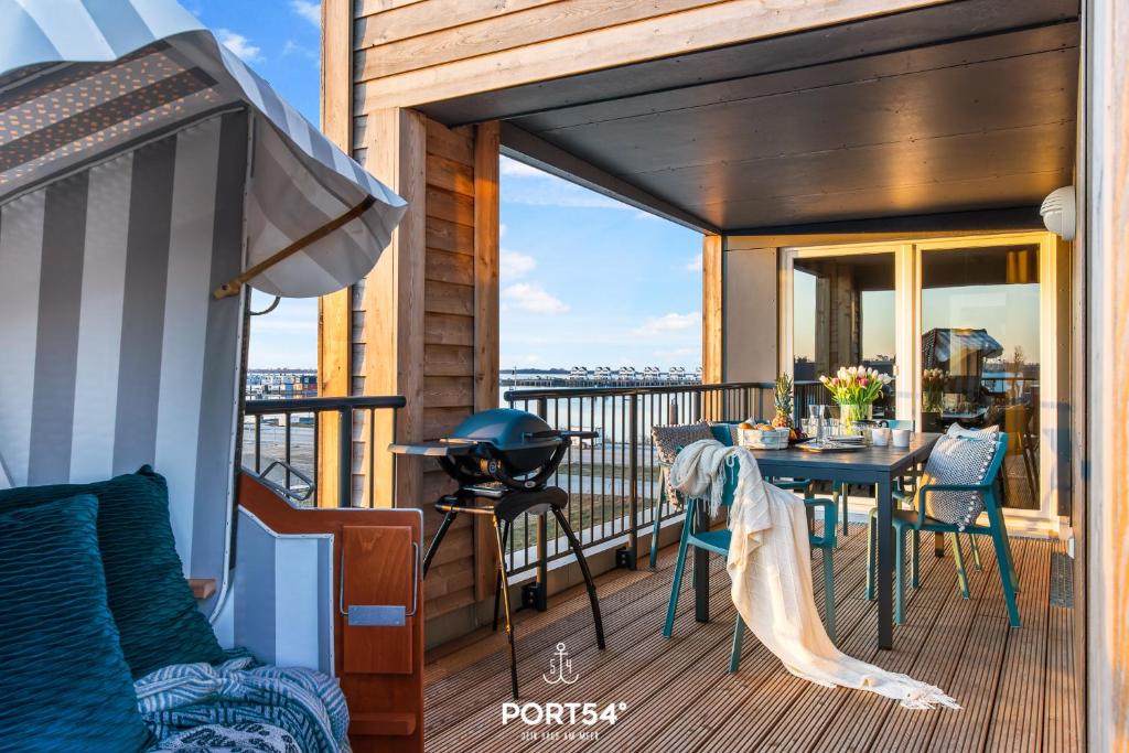 einen Balkon mit einem Tisch, Stühlen und einem Grill in der Unterkunft Strand Loft in Olpenitz