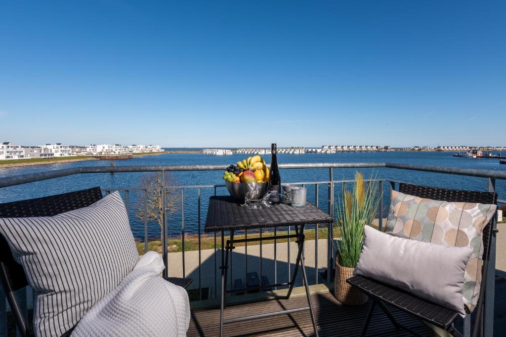 - un balcon avec deux chaises et une table avec un bol de fruits dans l'établissement Marinablick, à Olpenitz