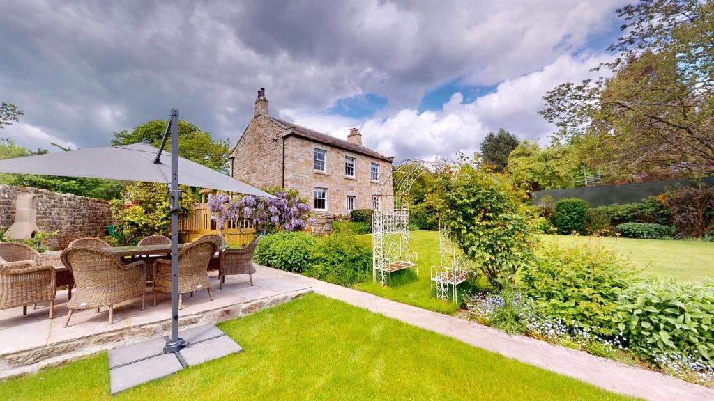a garden with a table and an umbrella at Nidd House Farm in Harrogate