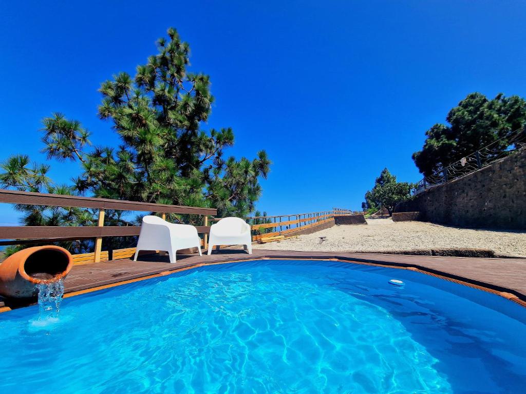 - une piscine avec 2 chaises blanches à côté d'une plage dans l'établissement Laurelin, à Candelaria
