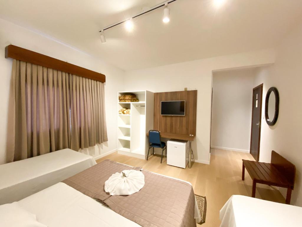 um quarto com 2 camas, uma secretária e uma televisão em Hotel Raul's em Gaspar