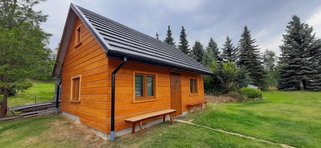 a small wooden cabin with a bench in a field at GAJÓWKA JAMNA NOCLEGI in Jamna