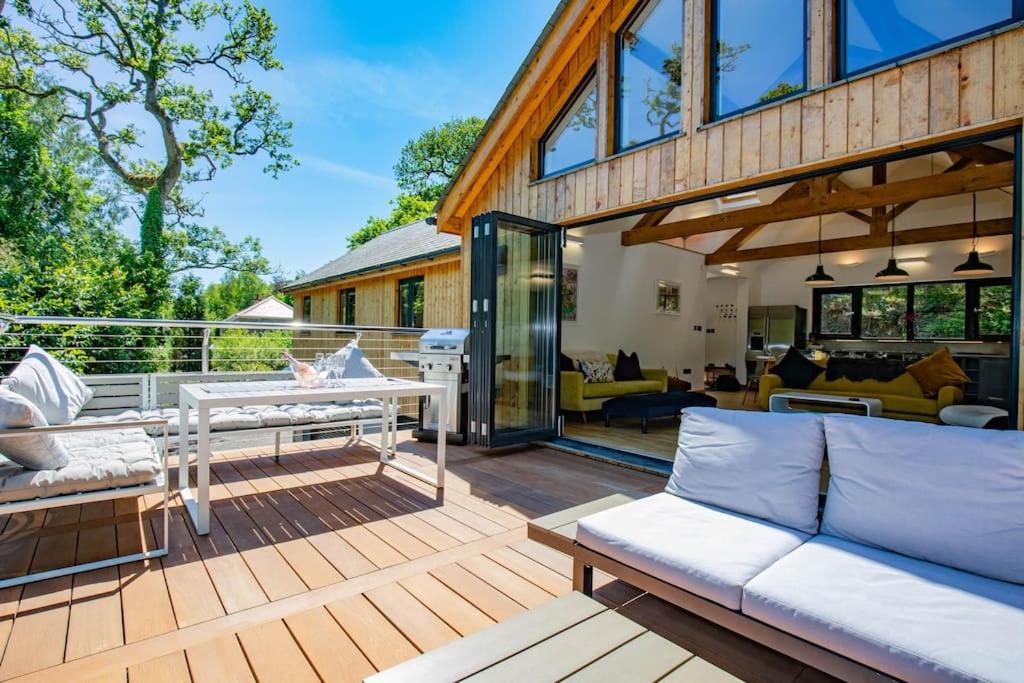 a wooden deck with a couch and a table at Tresillian Lodge Waterfront, Forest, Hot tub,Sauna in Truro