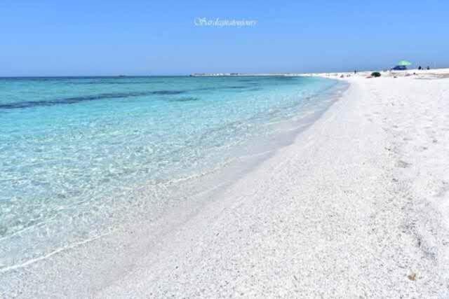 una playa blanca con agua azul y el océano en Residenza Sinis, en Cabras